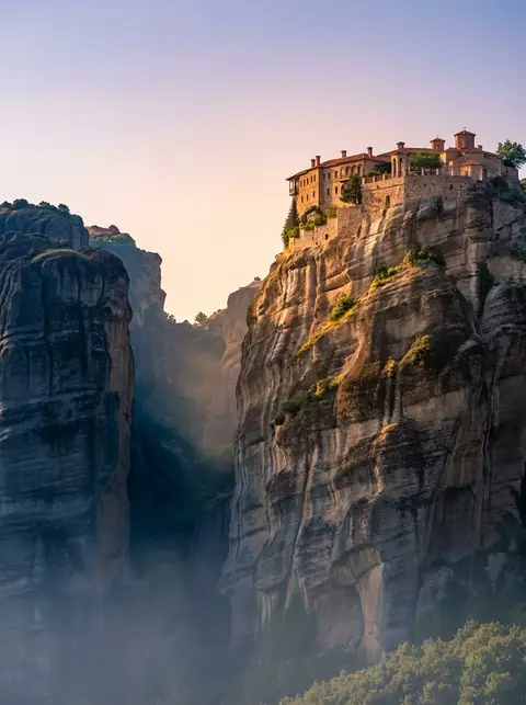 A Meteora monastery crowning its sandstone pillar above the morning haze