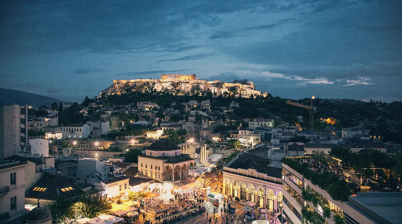 The Acropolis lit at dusk above the rooftops and lanes of Plaka