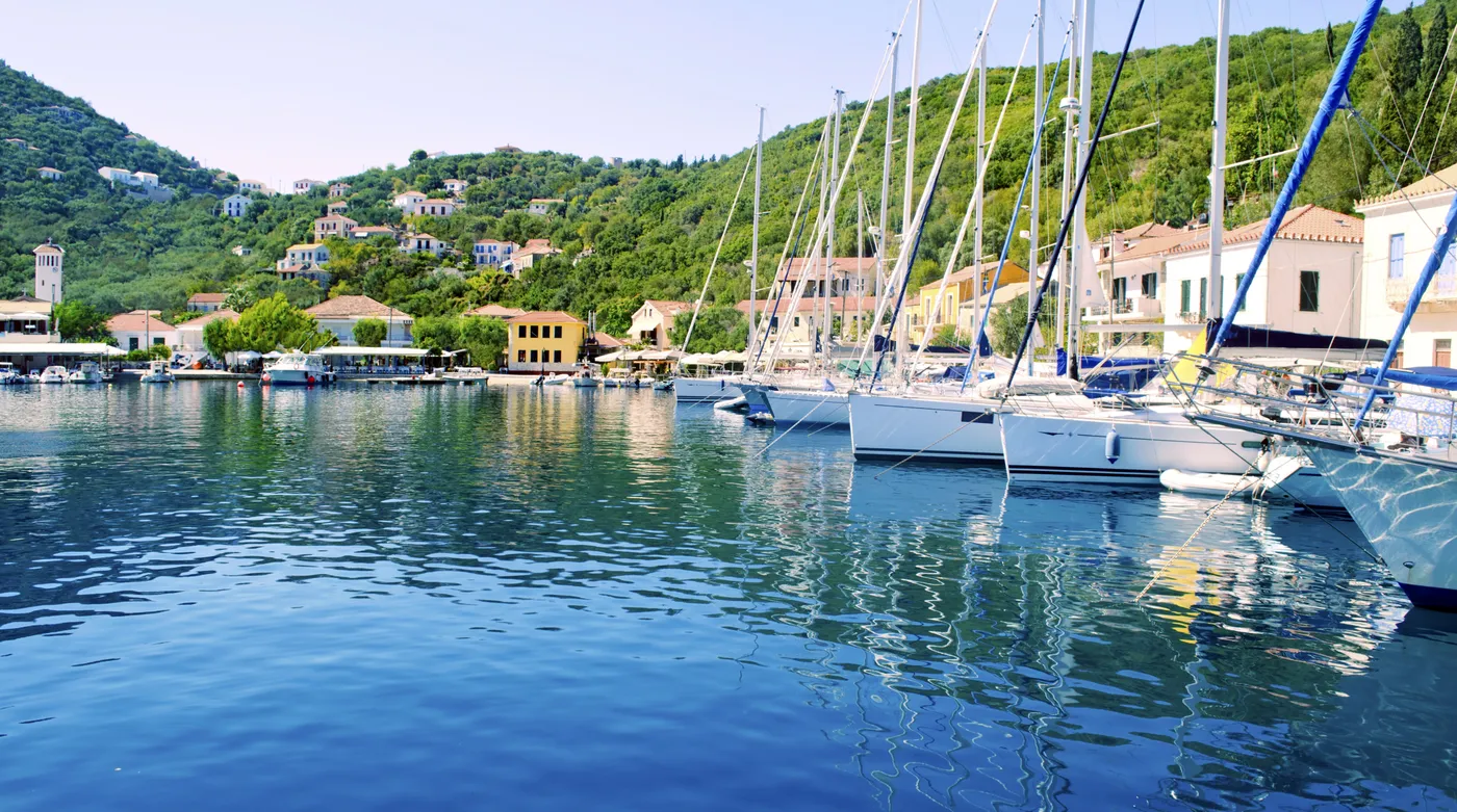 Sailing yachts stern to the quay at Kioni on Ithaca, green hills closing the bay