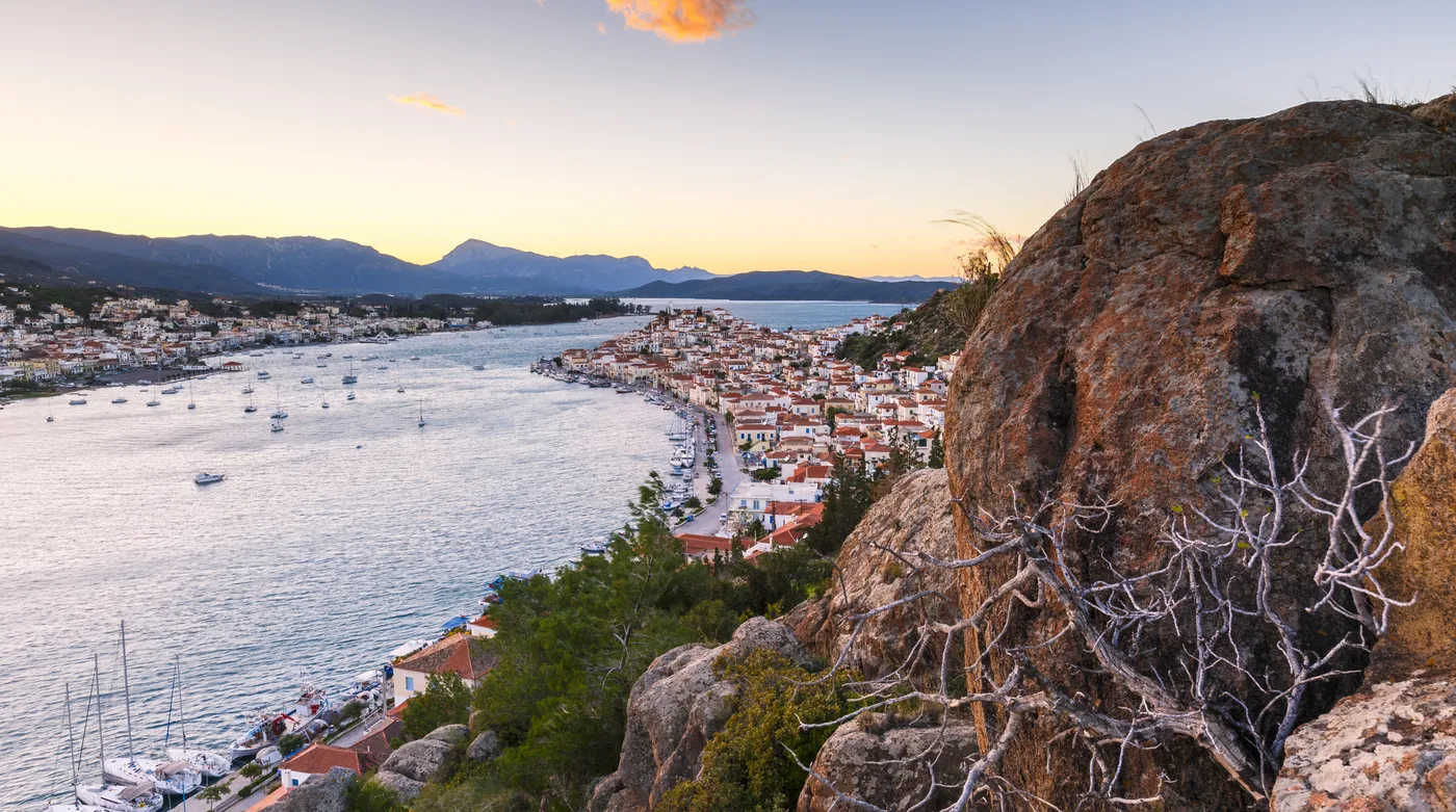 Poros town rising from its waterfront in the last light, boats along the quay