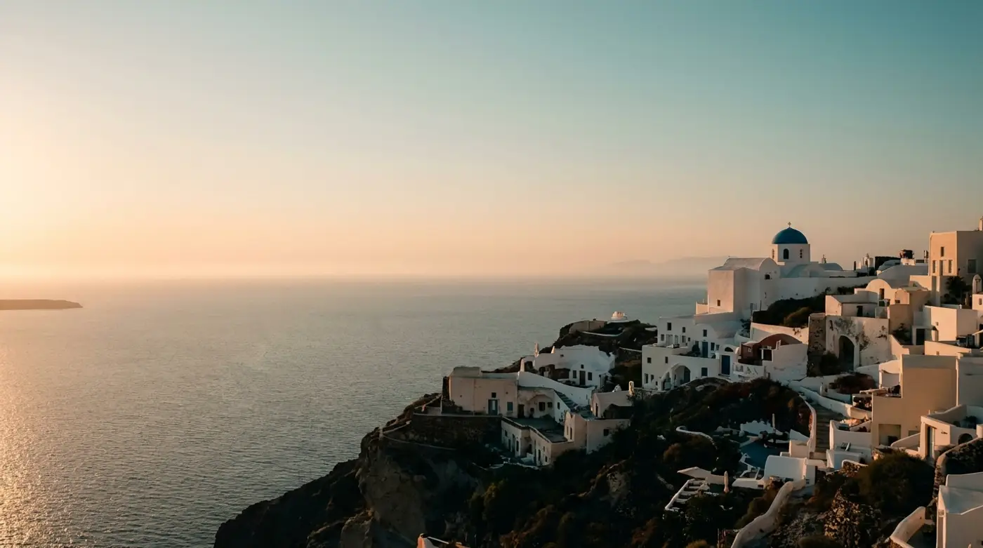 Whitewashed village of Oia on the edge of the Santorini caldera at golden hour, with the Aegean sea below