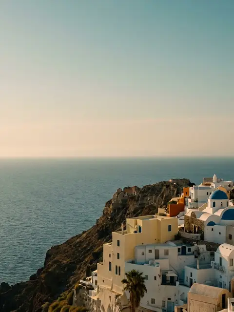 Whitewashed houses of Oia stacked above the Santorini caldera in warm evening light